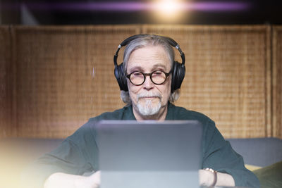 Senior man with headphones using tablet