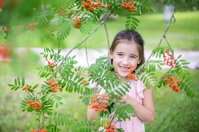 Portrait little girl with long hair smiling and holding a bunch of rowan berries in her hand