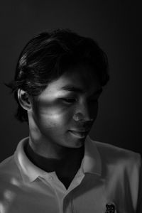 Close-up portrait of young man against black background