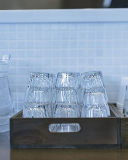 Stacked empty glasses in wooden tray on kitchen counter
