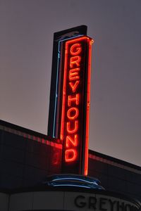 Low angle view of illuminated sign against clear sky at night