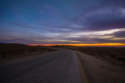 Road amidst land against sky during sunset