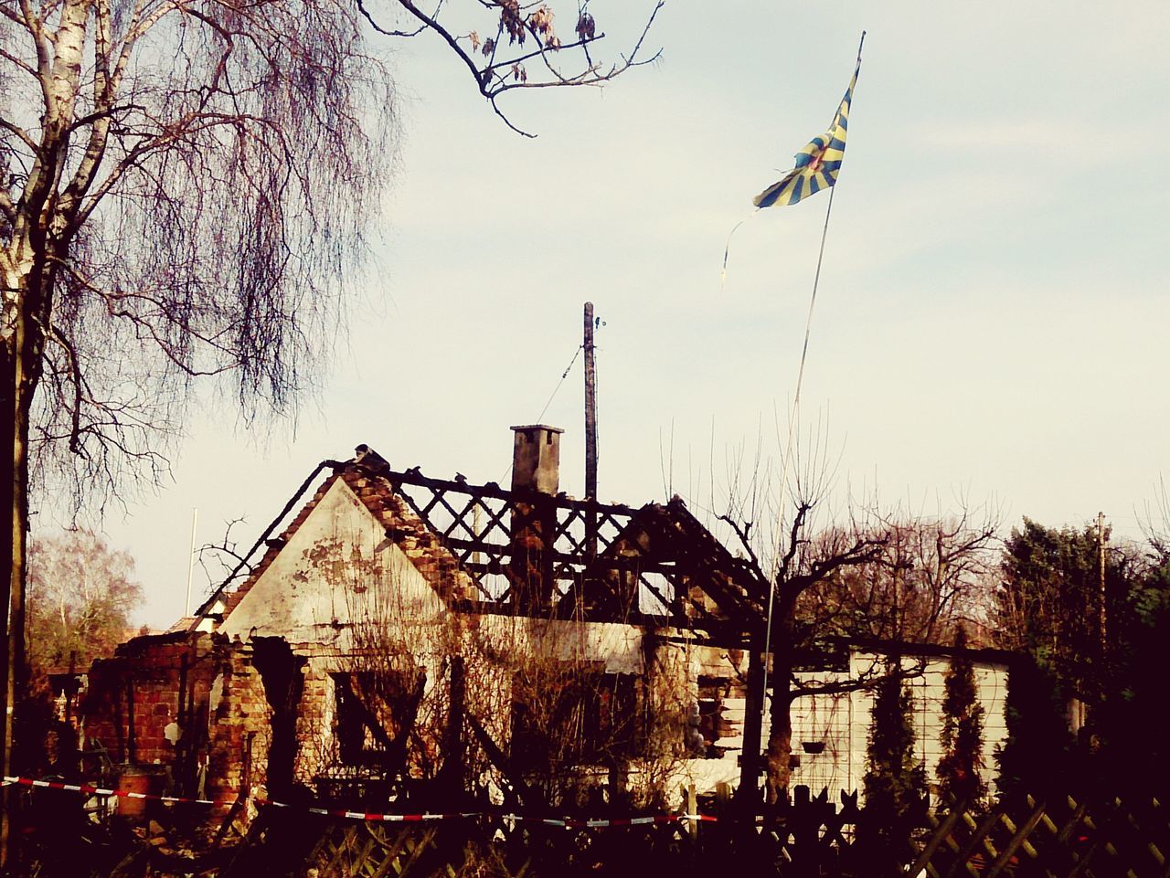 building exterior, architecture, built structure, tree, sky, low angle view, house, clear sky, bare tree, outdoors, no people, residential structure, day, old, tower, traditional windmill, fuel and power generation, religion, rural scene, construction site