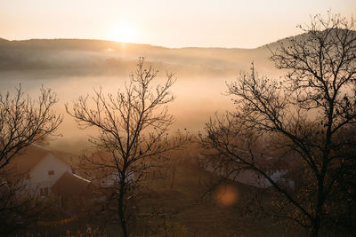 Foggy sunrise landscape in autumn mountains village