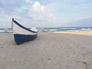 Boat moored on beach against sky