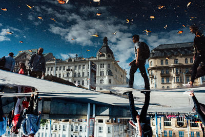 People walking by buildings against sky in city