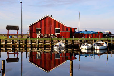 Boats moored in lake by building against sky