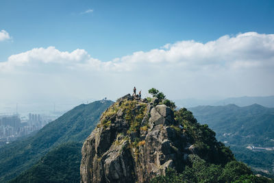 Hikers standing on top of mountain against sky