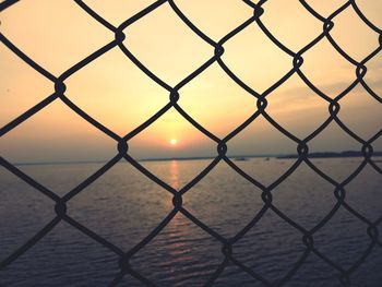 Scenic view of sea seen through chainlink fence