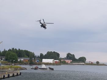 Helicopter flying over river against sky