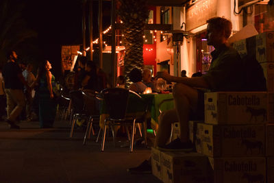 People sitting on table in illuminated city at night