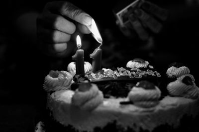 Midsection of woman igniting candle on cake