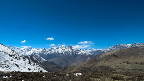 Scenic view of snowcapped mountains against blue sky