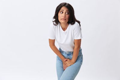 Portrait of young woman standing against white background