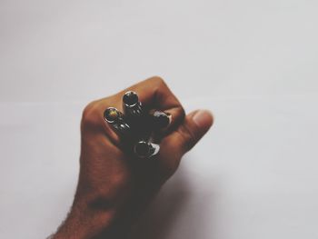 Cropped hand holding pens over white background