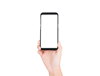 Close-up of hand holding smart phone against white background