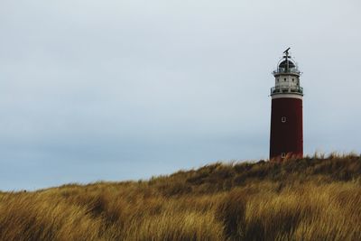 Lighthouse on field against sky