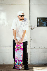 Man wearing sunglasses standing against wall