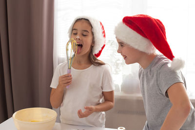 Children in red caps cheerfully cook cookies in the kitchen.