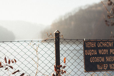 Text on chainlink fence against sky