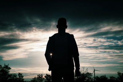 Rear view of silhouette man standing against sky during sunset