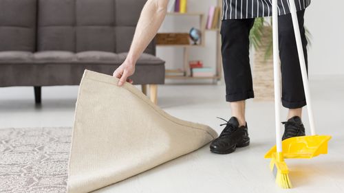 Low section of man standing cleaning floor at home