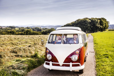 Happy couple inside van in rural landscape