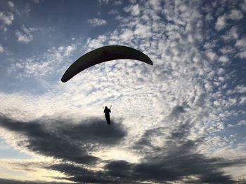 Low angle view of person paragliding against sky