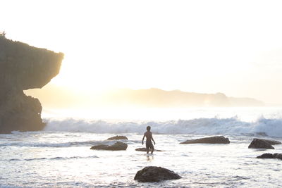 Rear view of woman standing on beach against sky