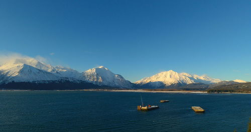 Scenic view of sea and mountains against clear blue sky