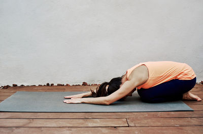 Woman lying on floor against white wall