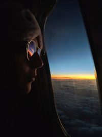 Man looking through airplane window against sky