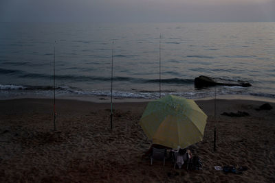 Rear view of people on beach against sky during sunset