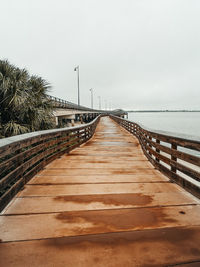 Wooden footbridge over sea against clear sky