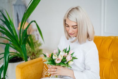 Girl on a yellow sofa with a bouquet of spring flowers