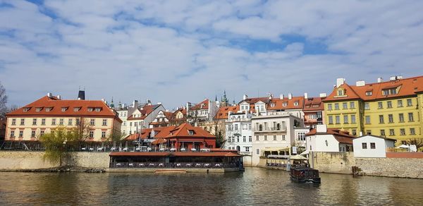 Buildings by river against sky in city