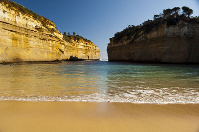 Rock formations by sea against clear sky