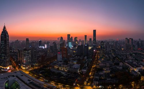 Aerial view of illuminated cityscape against sky during sunset