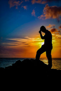 Silhouette man on beach against sky during sunset