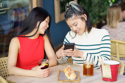 Smiling friends using mobile phone at home