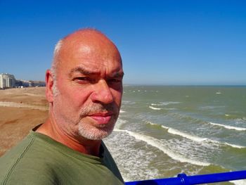 Portrait of man standing at beach against clear blue sky