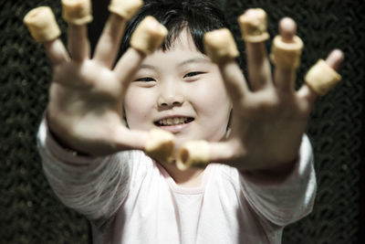 Close-up portrait of girl with snacks on fingers