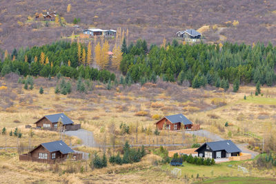 Built structure on field by houses against trees