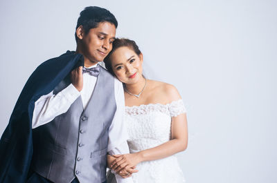 Portrait of young couple standing against white background