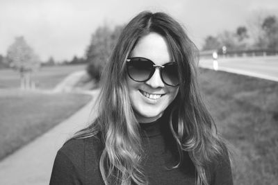 Portrait of smiling young woman standing on road at park