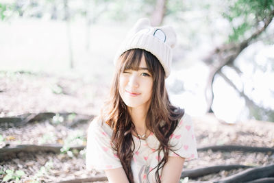 Portrait of beautiful young woman winking in forest