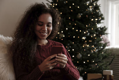 Happy young woman using smart phone at home