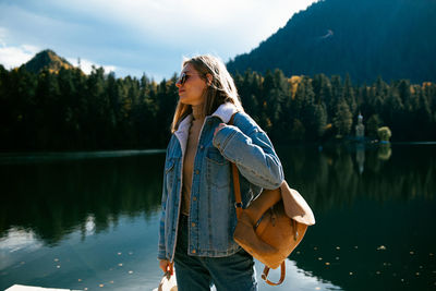 Woman standing by lake against trees