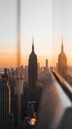 Empire state building seen through window in city during sunset