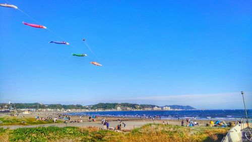 People on beach against clear blue sky